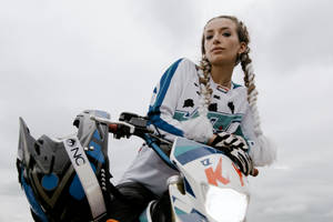 年輕女子穿著越野摩托車裝備，在陰天騎著越野摩托車。
