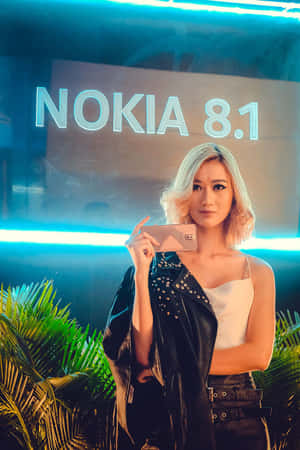 女性在Nokia 8.1發布活動中於霓虹燈下手持電話擺姿勢。 — Nokia 壁紙
