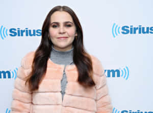 身穿桃色皮草外套的女性在SiriusXM標誌牆前對著鏡頭微笑。 — 瑪麗蓮·夢露 壁紙