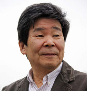 一位灰白頭髮的年長亞洲男子穿著棕色外套和條紋襯衫，露出溫柔的微笑。 — 場地圭介 壁紙