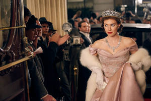 一位身穿粉紅色禮服和頭冠的女王在攝影師的包圍下走下火車。 — 玫瑰金風格 壁紙