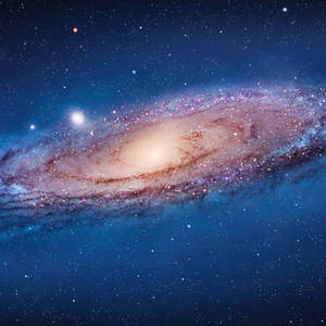 一個帶有發光旋臂和散落恆星的螺旋星系。 — 銀河 壁紙