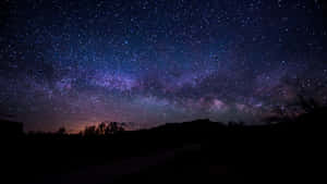 在星空下帶有紫色銀河的黑暗山丘 — 夜空 壁紙