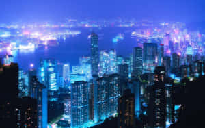 夜間城市天際線，擁有明亮的摩天大樓和閃閃發光的水濱。 — 城市景觀 壁紙