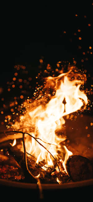 一個在黑暗的夜晚溫暖地燃燒的噼啪作響的營火。 — IQOO 壁紙