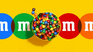 一碗色彩繽紛的M&M's糖果，周圍環繞著品牌標誌圓圈。 — 朱古力 壁紙