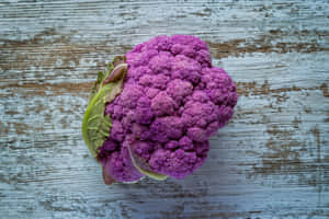 一個紫色椰菜花放在風化的木質表面上。 — 紫色花朵 壁紙