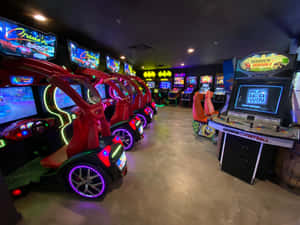 一個光線明亮的遊戲機中心，設有賽車模擬器和Madden Football遊戲機。 — 街機 壁紙