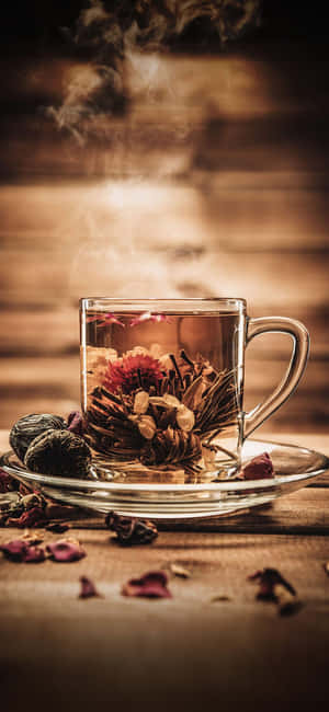 木桌上玻璃杯中的冒煙花草茶與乾燥花 — Huawei 壁紙