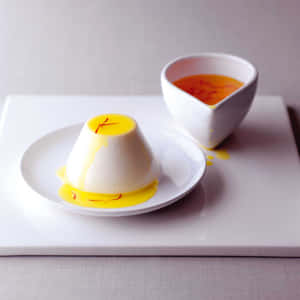 白色碟子上配有藏紅花裝飾和醬汁的奶油意式奶凍。 — 甜品 壁紙