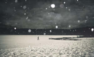 一個人在雪夜天空下獨自走在冰凍的湖面上。 — 暮光 壁紙
