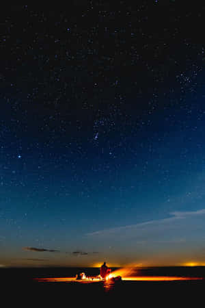 人物坐在營火旁，星空下 — 2:3 壁紙