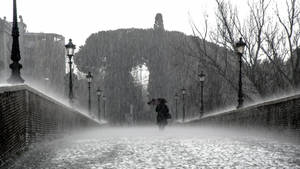 一個人在雨中撐傘走在有路燈的石橋上。 — 雨天 壁紙