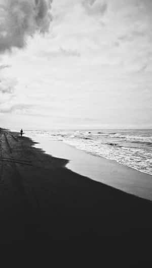 一個孤獨的人沿著黑暗的海灘行走，海浪在陰天中翻滾。 — 海灘 壁紙