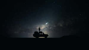 一個人在車輛上的剪影，在星空下凝視著銀河。 — 星星 壁紙