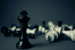 一個黑色國際象棋國王高高站立，而倒下的白色棋子散落在後面。 — Surface Pro 壁紙