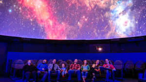 家庭在天文館觀看色彩繽紛的星空投影。 — 月色夜空 壁紙