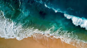 碧綠色的海浪在金色沙灘上破碎的鳥瞰圖。