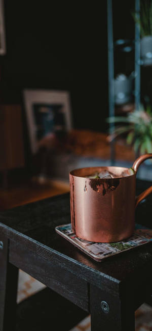 深色木桌上杯墊上的帶冰銅杯，舒適的房間 — 三星 Galaxy S20 壁紙