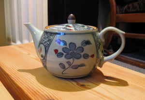 一個裝飾性的陶瓷茶壺，上面有藍色花朵，放在木桌上。 — 溫馨聖誕美學 壁紙