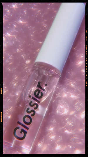 Glossier 唇彩瓶在帶有閃爍效果的粉紅色泡泡背景上。 — 9:16 壁紙