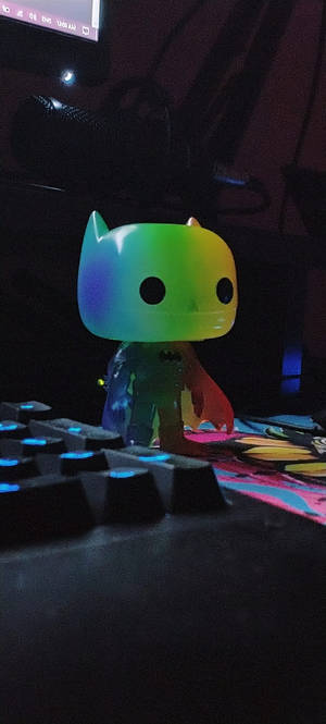 在黑暗遊戲設置中的發光鍵盤上的彩虹蝙蝠俠Funko Pop。 — 超級英雄 壁紙