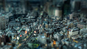 一個微型城市，在黃昏時有模糊的建築物和發光的街燈。 — 天際線 壁紙
