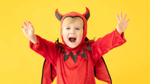一個開心嘅幼兒打扮成魔鬼，舉起雙臂。 — 萬聖節恐怖 壁紙