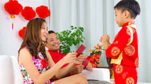 父母在室內農曆新年慶祝活動中給孩子派發紅包。 — 中文 壁紙