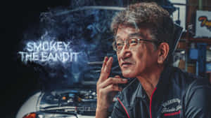 男人吸煙，煙霧在車庫的汽車上方拼出「Smoky the Bandit」。 — 肖像 壁紙