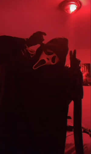 在紅色燈光房間中做出和平手勢的Ghostface面具人物。 — Galaxy Tab A 壁紙