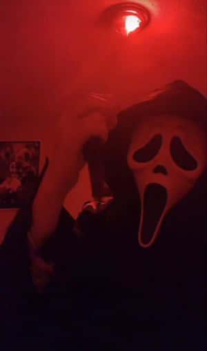 戴著Ghostface面具的人，在紅色燈光的房間裡拿著刀。 — 鬼滅之刃面具 壁紙