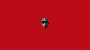 一個戴著綠色帽子的男人臉部，在紅色背景上居中。 — Tyler the creator GIF 壁紙