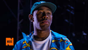 音樂家在聚光燈下的舞台上穿著彩色外套和帽子。 — Tyler the creator GIF 壁紙