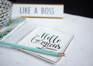 一支薄荷色鉛筆放在一個寫著「Hello Gorgeous」的杯墊上，旁邊有一個「Like a Boss」標誌，放在大理石桌上。 — 團隊合作 壁紙