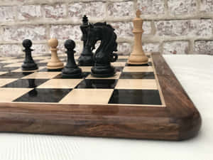 木製棋盤，帶有黑色和淺色木製棋子，背景為磚牆。 — 國際象棋 壁紙