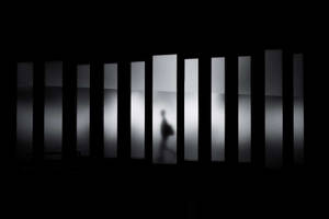 模糊的人影在黑暗中穿過發光的垂直面板。 — 黑白 壁紙