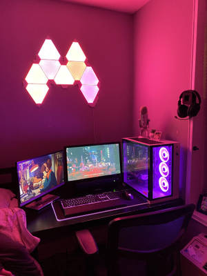 在粉紅和紫色燈光下，配備雙顯示器和發光PC機箱的遊戲桌。 — 遊戲 壁紙