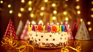 生日蛋糕，上面有點燃的蠟燭和派對帽，放在節日的桌子上。 — 生日蛋糕 壁紙