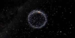 一個閃爍粒子環在深空中繞著一顆黑暗行星運行。 — 省電 壁紙