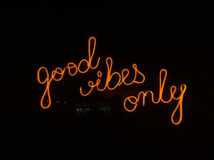 夜間發出橙色光芒、寫有 good vibes only 的霓虹燈牌。 — 霓虹美學 壁紙