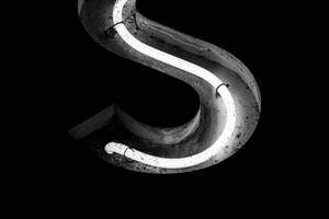 一個發光的霓虹字母S嵌入混凝土中，背景為黑色。 — 黑白 壁紙