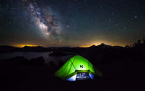 一個發光的綠色帳篷在星空下，銀河在湖泊上空。 — 沙灘度假 壁紙
