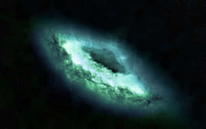 一個明亮的綠色螺旋星系漂浮在佈滿星星的黑色虛空中。 — 2880x1800 壁紙