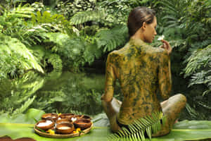沾滿泥巴的女人坐在叢林池塘邊拿著白花 — 叢林動圖 壁紙