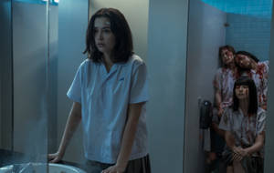 穿校服的女孩站在浴室，血淋淋的同學從隔間出現。 — Netflix GIF 壁紙
