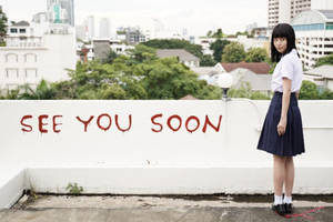 一個穿著校服的女孩站在屋頂上，身後的白牆上有「SEE YOU SOON」塗鴉。 — 日出 壁紙