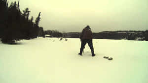 一個人喺雪地入面獨自行走，背景有樹同山丘。 — 冰 GIF 壁紙