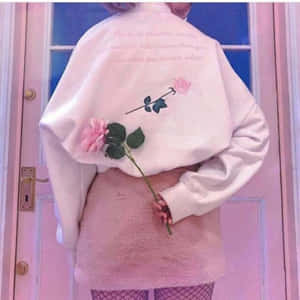 穿著毛絨粉紅色服裝的人手持玫瑰站在粉紅色門前。 — 熱粉紅美學 壁紙