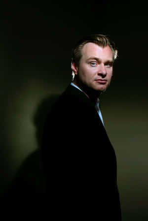 穿著深色西裝的男人站在燈光戲劇化的攝影棚中。 — 攝影師 壁紙